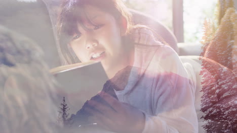 composite of smiling woman reading book, and sun on trees and mountainside