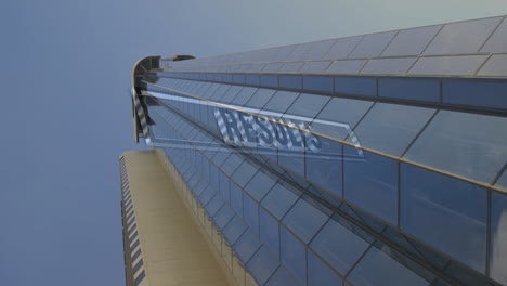 modern skyscraper rising against clear sky, showing reflective glass panels and metal framing