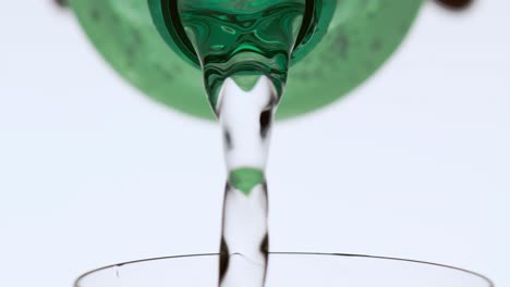 person filling a glass with liquid from a bottle