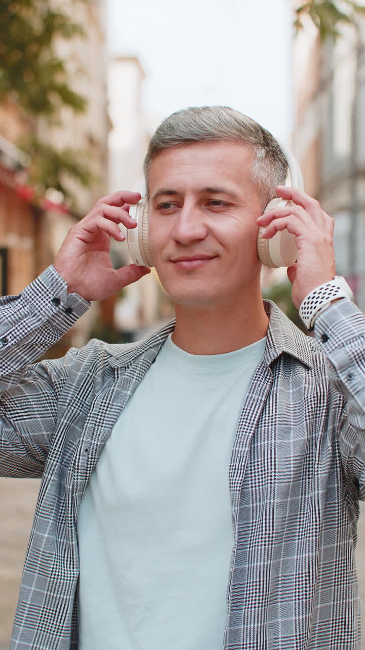 Happy mature man listening favorite energetic disco rock n roll music dancing outdoors