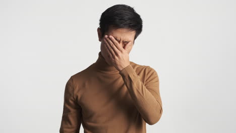 피곤한 아시아인 남자가 안경을 벗고 있다.