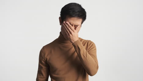 un hombre asiático cansado quitándose las gafas.