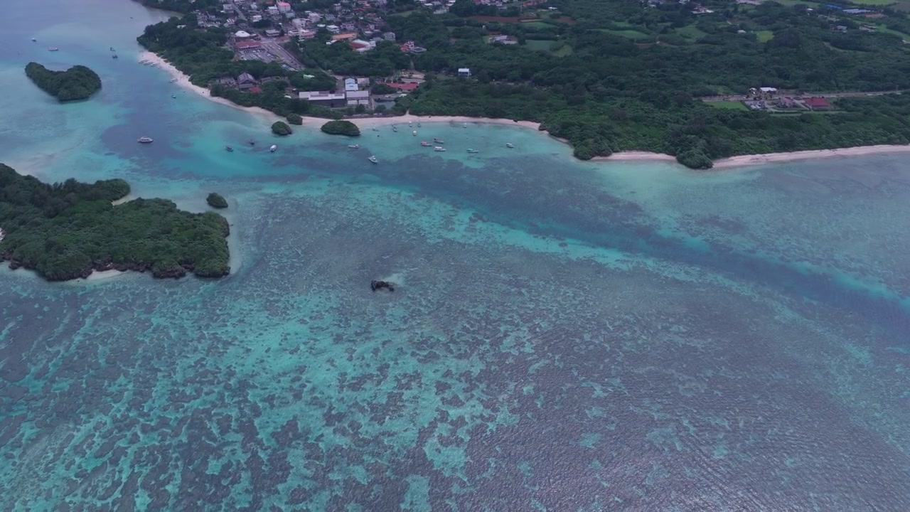 Inquadratura orizzontale ravvicinata con carrello in avanti da un'angolazione obliqua elevata sopra le acque turchesi e le barriere coralline vicino alla Baia di Kabira, Okinawa, Giappone.