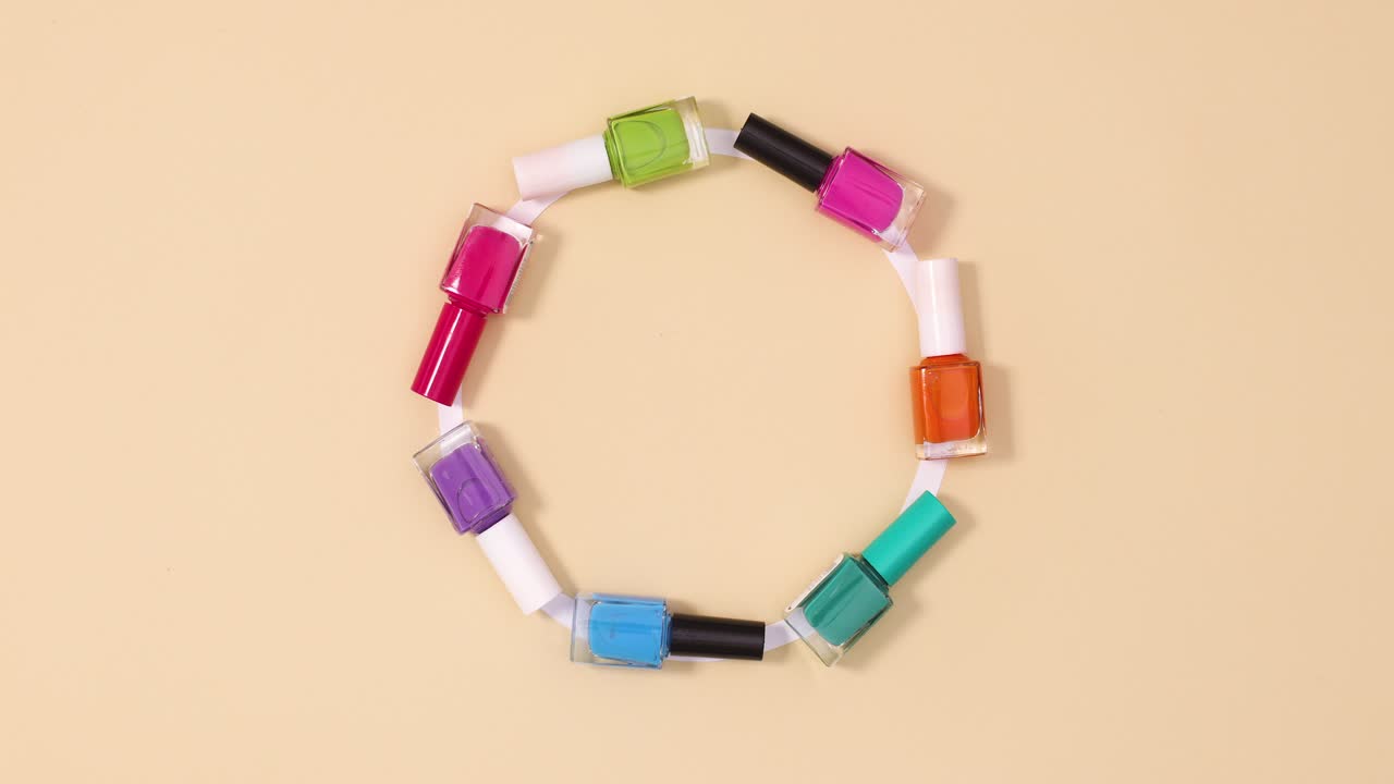 творческие лаки для ногтей бутылки в разных цветах движутся в круге с копировальным пространством на бежевом фоне.