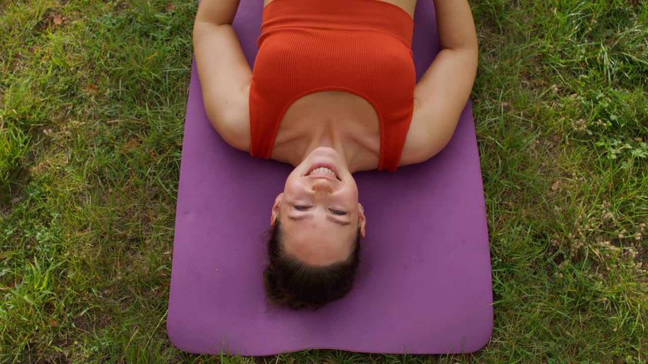 Donna che si rilassa su un tappetino da yoga all'aperto