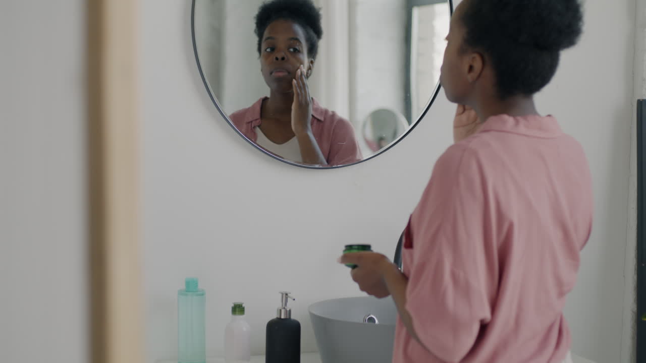 Woman Applying Face Cream in Bathroom