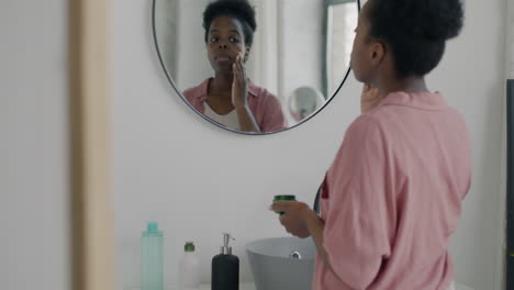 mujer aplicando crema para la cara en el baño