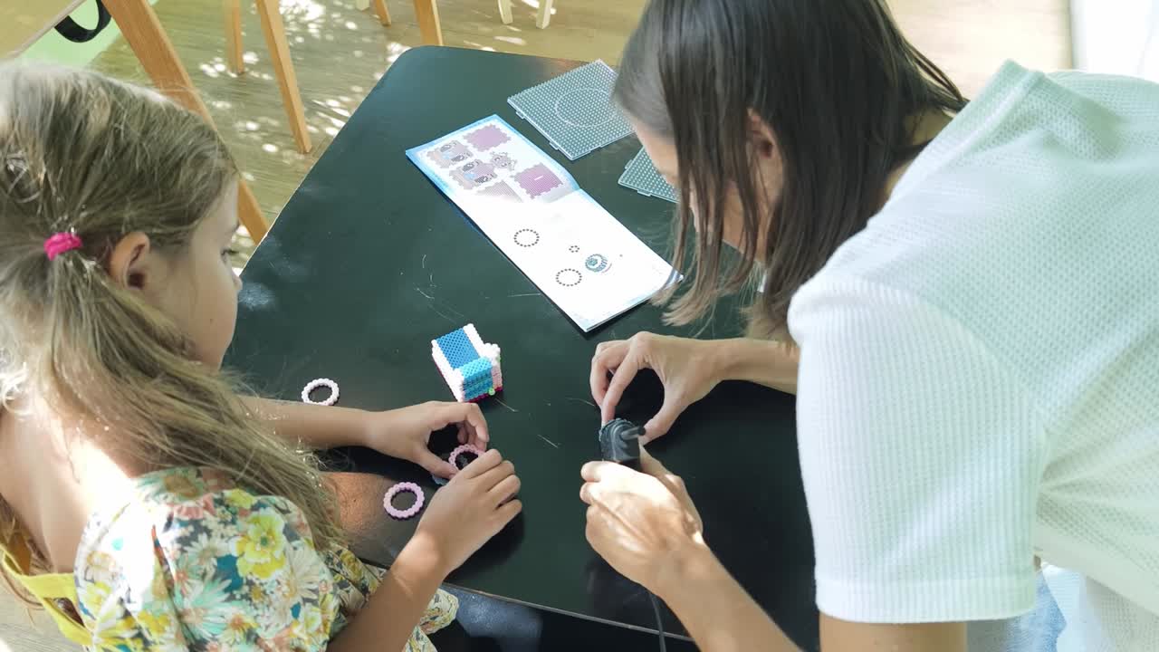 어머니 와 딸 이 구슬 을 는 공예 를 하고 있다