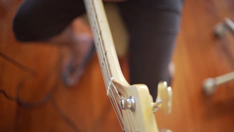 Overhead-orbital-view-of-male-caucasian-bassist-playing-the-bass-guitar-at-home-studio-sitting-on-chair-4K