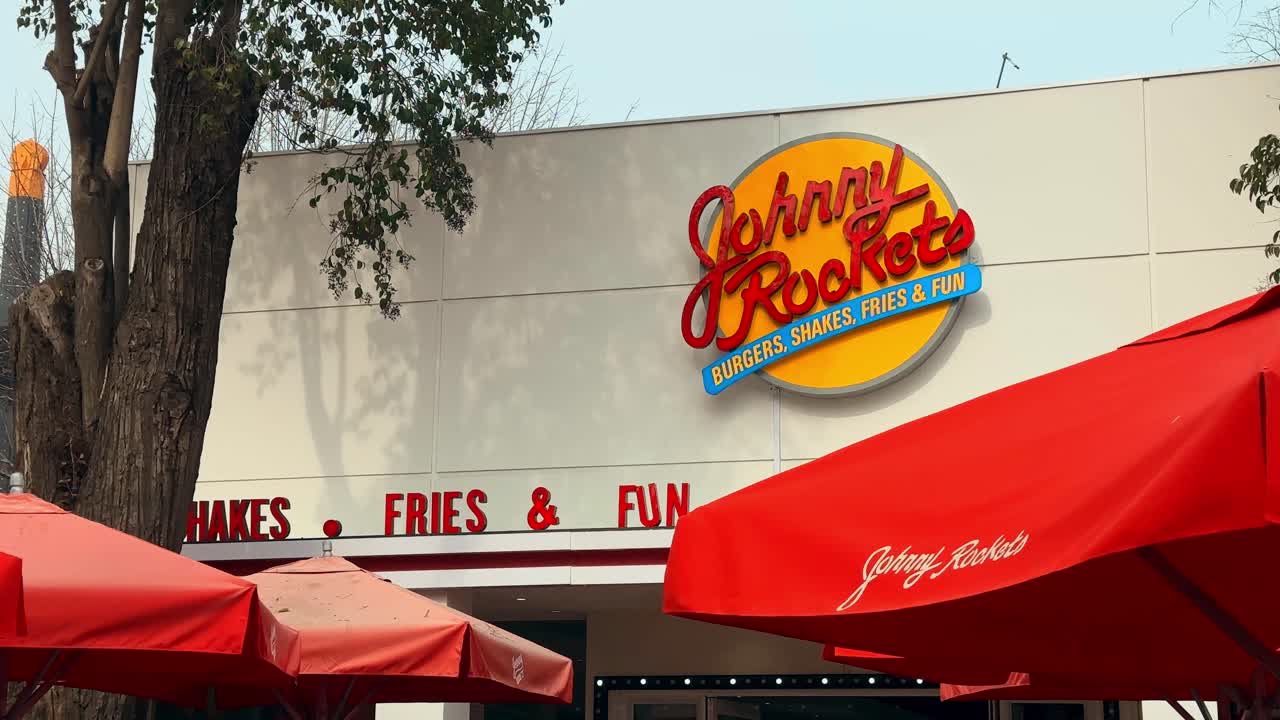 Establishing the red and yellow sign of the Johnny Rockets hamburger restaurant on a sunny, calm day.
