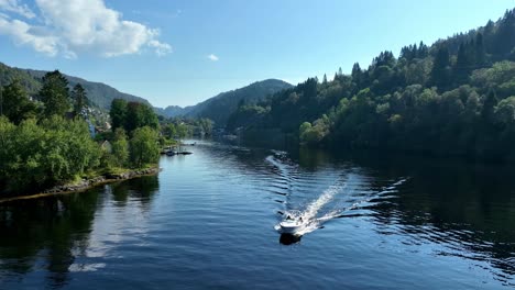 boat moves on calm fjord in hosanger with church on the headland in background. idyllic summer scene in western norway