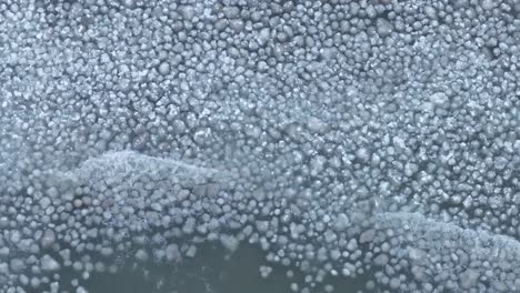 close-up of a frozen lake with ice patterns and bubbles trapped under the surface, cool and tranquil