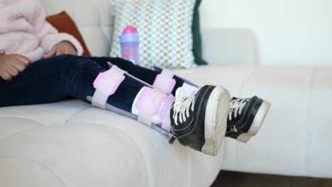 child in leg braces sitting on couch