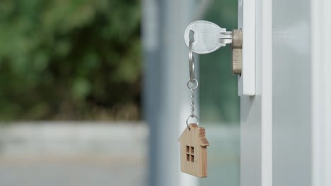 the house key for unlocking a new house is plugged into the door. the wooden keychain was moving as the wind blew. ready-to-live house concept