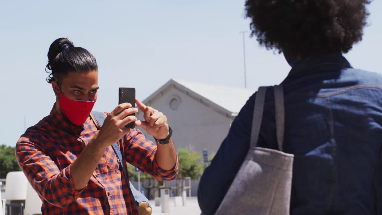 diversos colegas con máscaras faciales tomando fotos con un teléfono inteligente