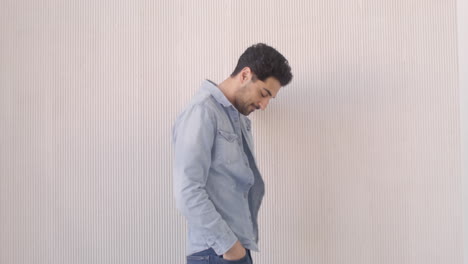 handsome dark haired man standing against the wall