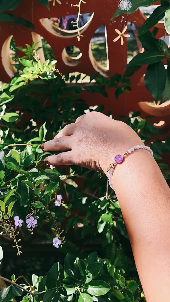 Woman's Hand with White Bead Bracelet in Garden