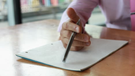 a bored office worker or possibly student at desk tapping his pen on a notepad in slow motion