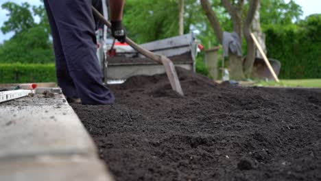 Trabajador-Extendiendo-La-Mezcla-De-Suelo-En-La-Cama-Del-Jardín,-Tiro-De-Bajo-Nivel