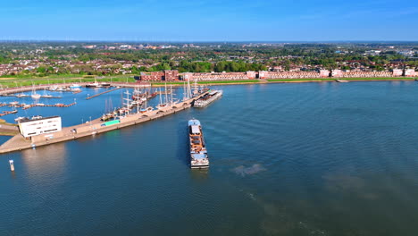 flying closer to the port on lake markemeer. ferry moves to the berth. panorama of lelystad, the netherlands at backdrop.