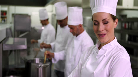 jefe de cocina sonriendo a la cámara con el equipo detrás de ella