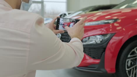 el gerente del concesionario toma fotos de un coche nuevo para la venta. sala de exhibición de coches nuevos de prestigio.