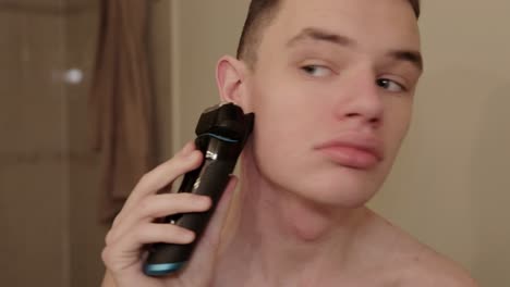 a young person shaves the stubble of their face