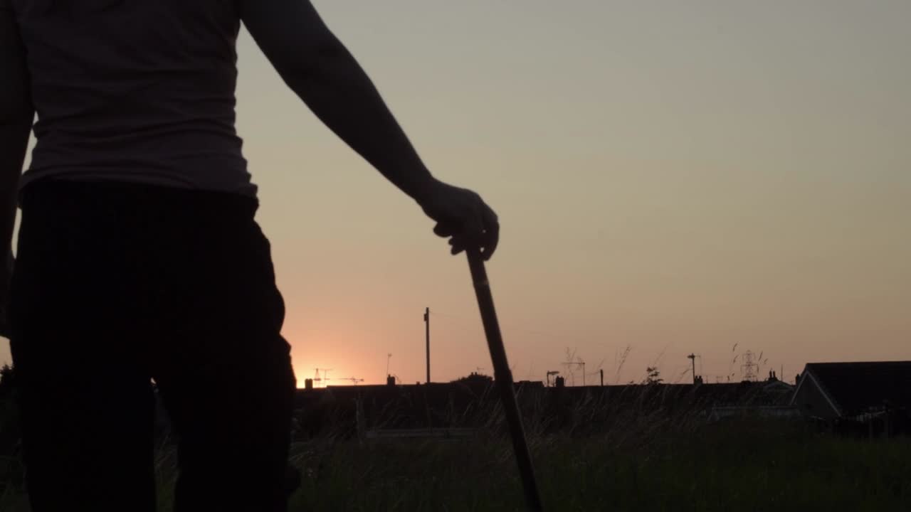 Silhouette di donna e bastone da passeggio al tramonto
