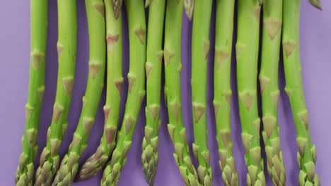 video of close up of fresh asparagus over lilac background