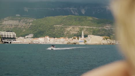 Blick-Auf-Die-Altstadt-Von-Budva-Mit-Einem-Boot,-Das-In-Zeitlupe-Darauf-Zufährt