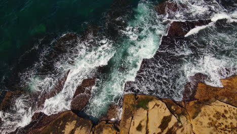 Vista-Superior-De-Múltiples-Olas-Oceánicas-Azules-Y-Verdes-Que-Se-Estrellan-Contra-La-Costa-Rocosa-En-Australia