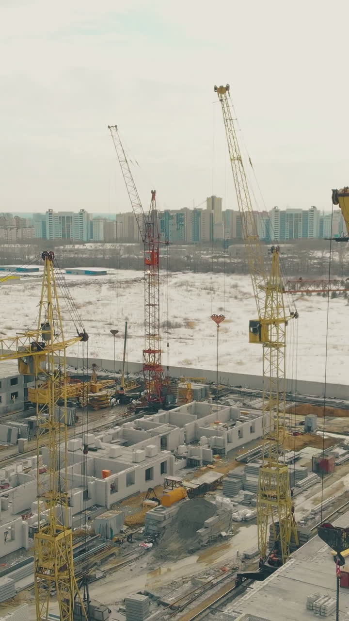 modern powerful tower cranes at apartment building construction site on nice winter weekend upper view