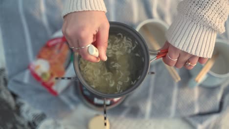 woman cooking ramen noodles outdoors
