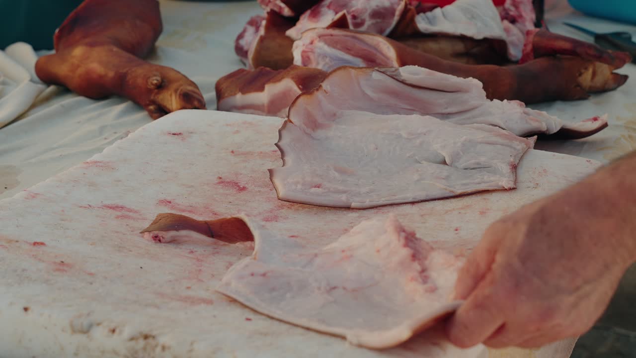 cut pig skin piece placed by hand on stained cutting board