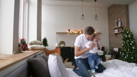 family, parenthood and people concept - happy father playing with little baby boy at home