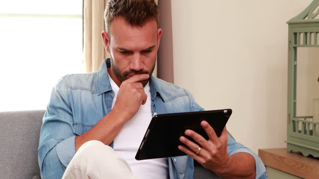 hombre guapo en el sofá usando la tableta