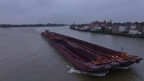 pushboat navigating past dordrecht with hull cutting through the water