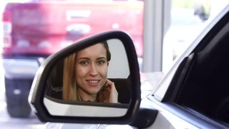 hermosa mujer conductor sonriendo a la cámara en el espejo lateral