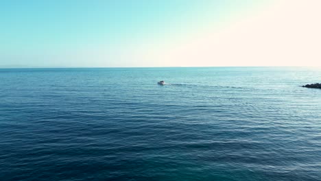 small yacht sailing away from the shore towards open sea on a journey in the summer