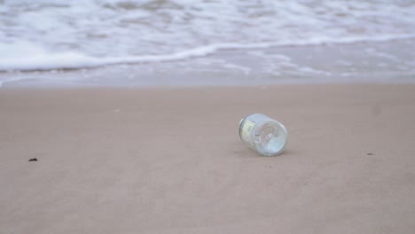botella de vidrio vacía en la playa, basura y basura en una playa vacía de arena blanca del mar báltico, problema de contaminación ambiental, día nublado, plano medio