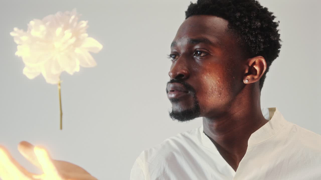 Young Black Man Contemplating Flower Levitating above His Hand