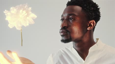 young black man contemplating flower levitating above his hand
