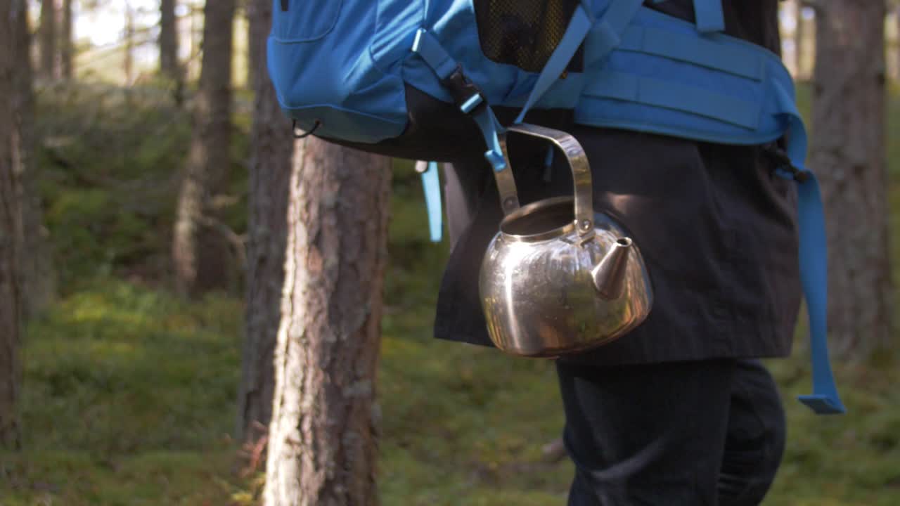 tetera de metal brillante con reflejo del bosque y atmósfera de cámara lenta otoñal, bolsa turística azul