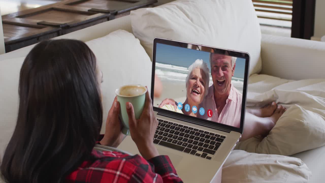 Mixed race woman on laptop video chat having coffee at home