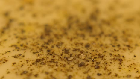 freshly mixed scrambled eggs in pan covered in crack black pepper. macro close up view showing high level of detail