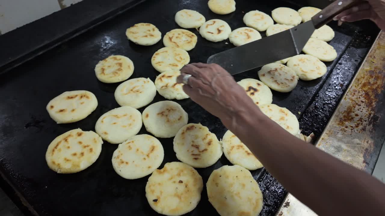 Rekaman genggam yang menangkap proses intensif pembuatan arepa jagung buatan sendiri untuk layanan yang sibuk