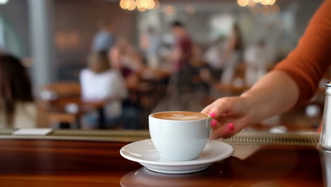 hand serving a latte in a busy cafe