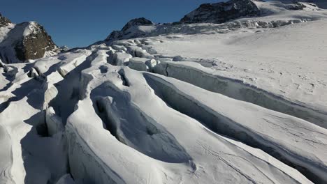 aerial view of a glacier with crevasses in the swiss alps, snow-covered holes