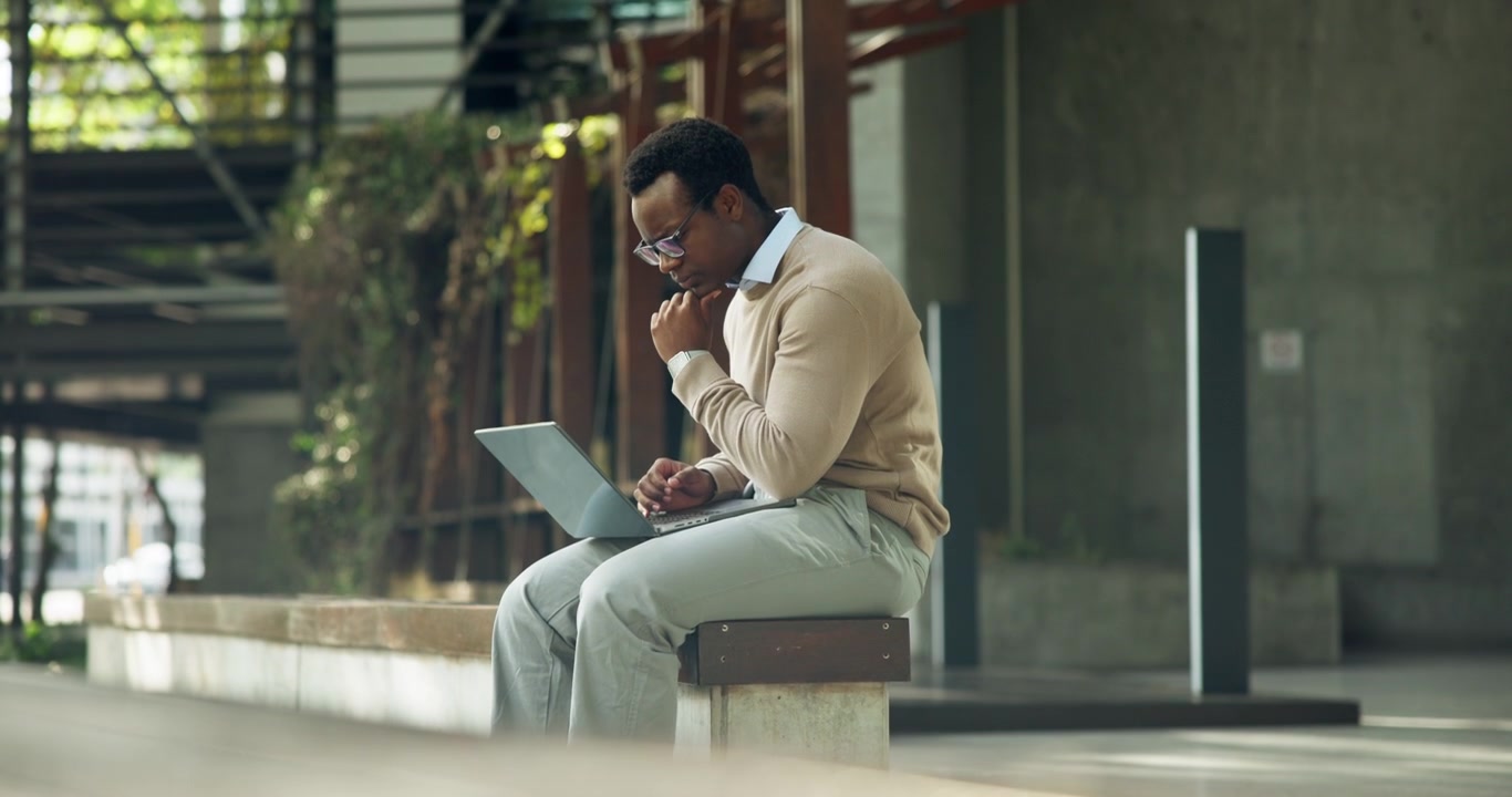 Focused Man Working on Laptop Outdoors in Modern Urban Setting