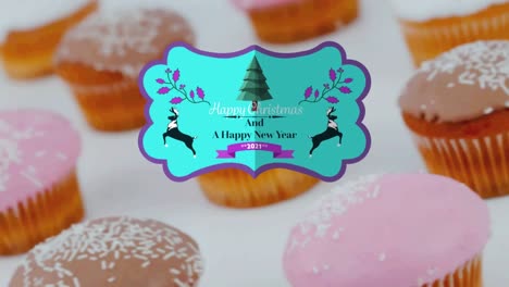 Animation-of-christmas-greetings-on-tag-over-cupcakes-on-white-background